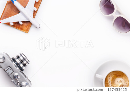 Travel-themed flat lay with toy airplane, camera, and coffee 127455425