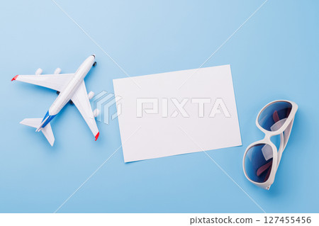 Travel-themed flat lay with blank photo card, sunglasses, toy airplane 127455456