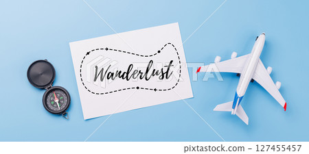 Travel-themed flat lay with card, compass, toy airplane 127455457