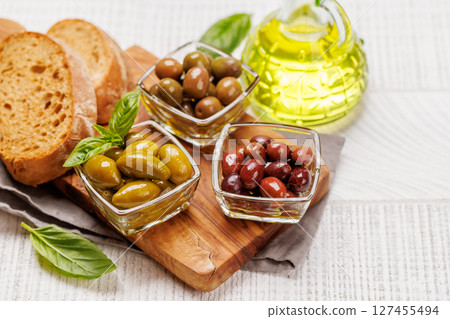 An assortment of various olives presented in a bowl, showcasing different colors, textures, and flavors 127455494