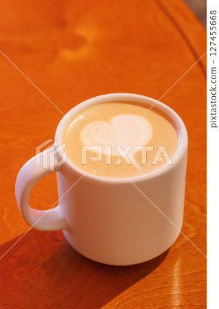 Warm cappuccino in a cup with heart-shaped latte art on top 127455668