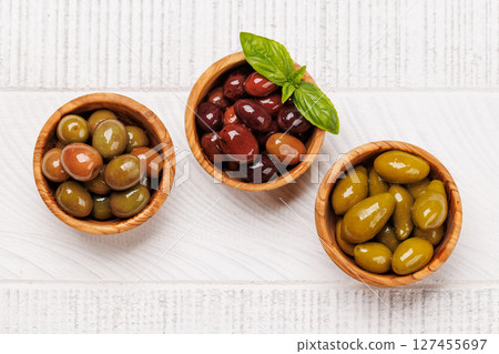 An assortment of various olives presented in a bowl, showcasing different colors, textures, and flavors 127455697