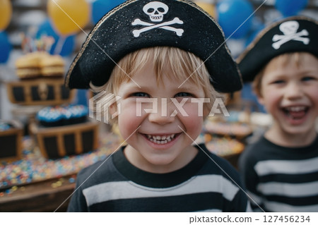 Two children dressed in pirate hats and striped shirts celebrate at a birthday party. 127456234