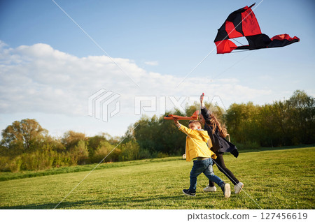 Clear sky. Two kids are playing with kite on the summer field Clear sky. Two kids are playing with kite on the summer field 127456619