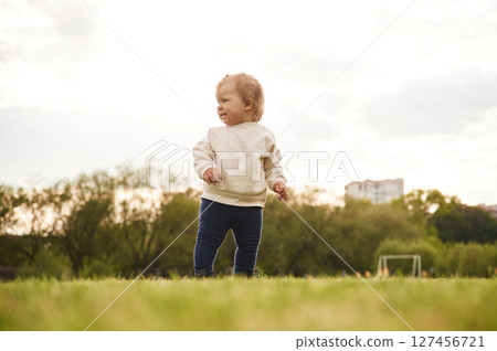 Little girl in casual clothes is on the summer field 127456721