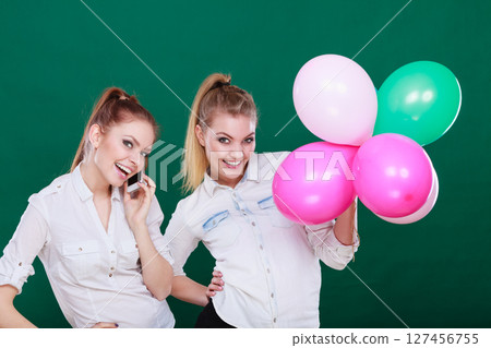 Two girls with mobile phone and balloons 127456755
