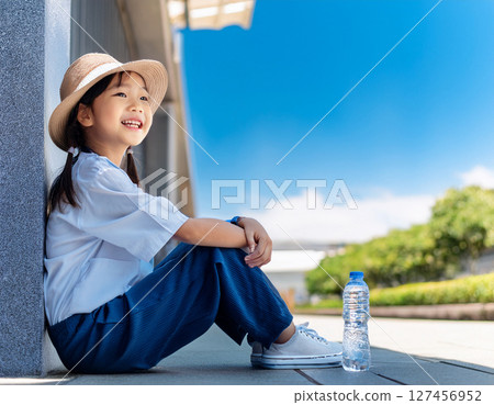 Elementary school students resting in the shade under the scorching sun 127456952