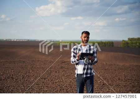 Digital tablet in hands. On cultivated agricultural field. Handsome Indian man Digital tablet in hands. On cultivated agricultural field. Handsome Indian man 127457001
