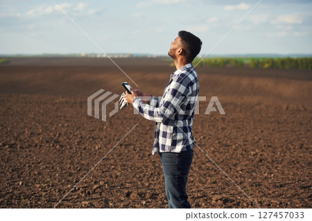 Black colored digital tablet in hands. On the cultivated agricultural field. Handsome Indian man Black colored digital tablet in hands. On the cultivated agricultural field. Handsome Indian man 127457033