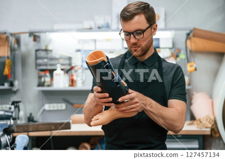 Holding prosthesis. Technician working in modern laboratory Holding prosthesis. Technician working in modern laboratory 127457134