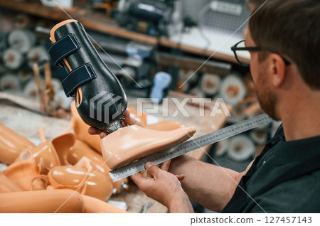 Measuring the prosthesis. Technician working in modern laboratory 127457143