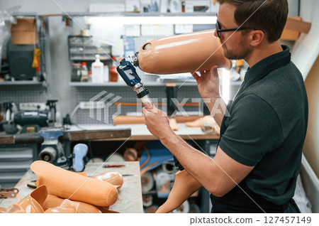 Checking the movement ability of product. Technician working with prosthesis in modern laboratory Checking the movement ability of product. Technician working with prosthesis in modern laboratory 127457149