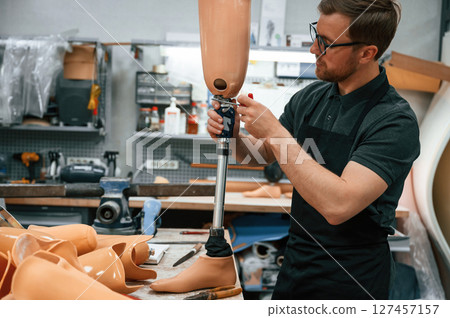 With prosthesis in hands. Technician working with prosthesis in modern laboratory 127457157