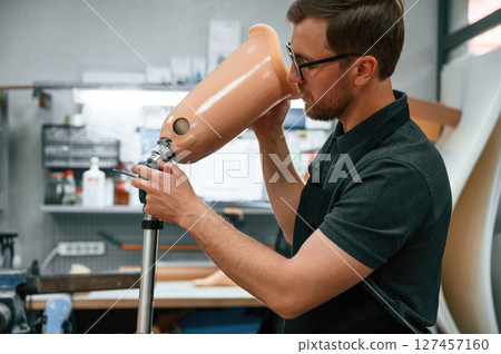 With prosthesis in hands. Technician working with prosthesis in modern laboratory With prosthesis in hands. Technician working with prosthesis in modern laboratory 127457160