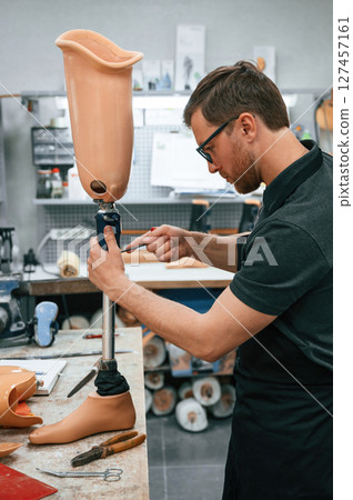 Assembles the prosthesis, using tool. Technician working in modern laboratory Assembles the prosthesis, using tool. Technician working in modern laboratory 127457161