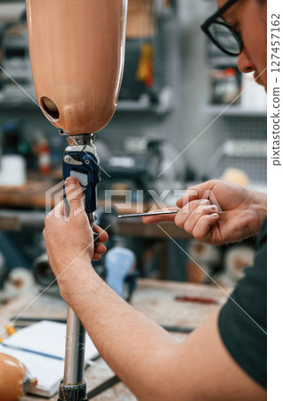 Assembles the prosthesis, using tool. Technician working in modern laboratory Assembles the prosthesis, using tool. Technician working in modern laboratory 127457162