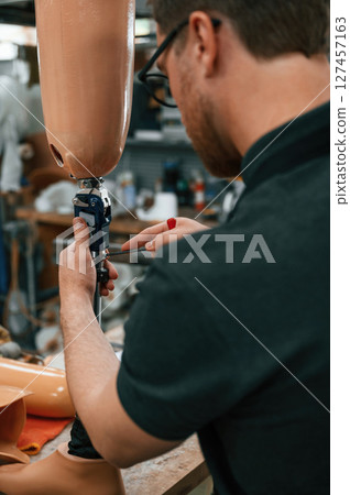 Assembles the prosthesis, using tool. Technician working in modern laboratory Assembles the prosthesis, using tool. Technician working in modern laboratory 127457163