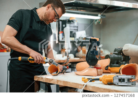 With drill. Technician working with prosthesis in modern laboratory 127457168