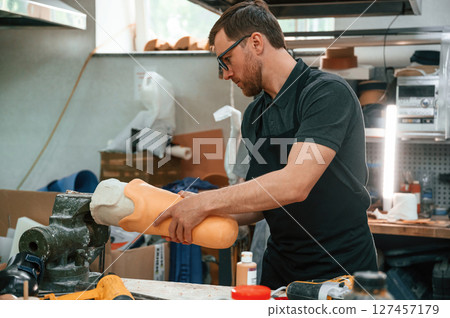 Leg prosthesis in hands. Technician working indoors 127457179