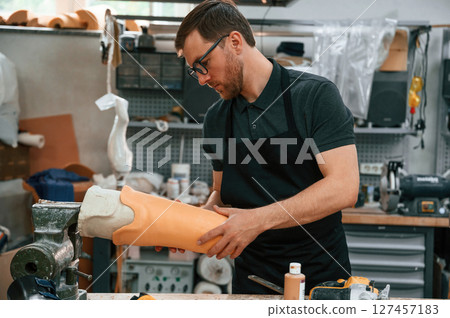 Almost finished product in hands. Technician working with prosthesis in modern laboratory 127457183