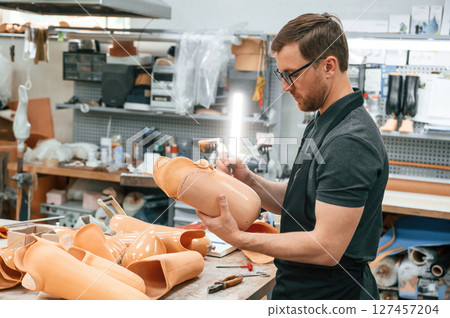 Using marker to draw the line. Technician working with prosthesis in modern laboratory Using marker to draw the line. Technician working with prosthesis in modern laboratory 127457204