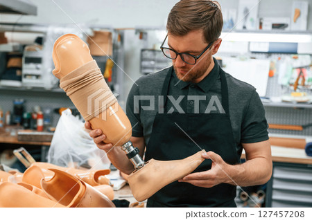 Leg prosthesis in hands. Technician working indoors 127457208