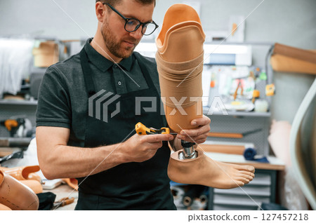 Tightening the screws. Technician working with prosthesis in modern laboratory 127457218