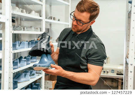 Man is holding shoe in the hands. Conception of industry Man is holding shoe in the hands. Conception of industry 127457229