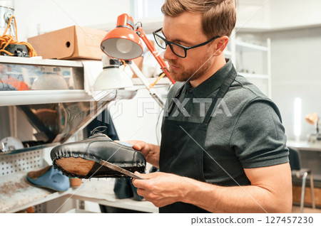Man is holding shoe in the hands. Conception of industry Man is holding shoe in the hands. Conception of industry 127457230