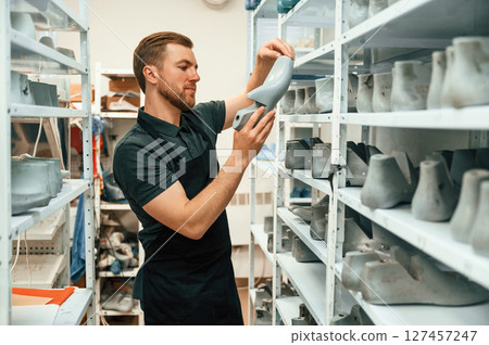 Shelves with shoes. Technician working indoors 127457247