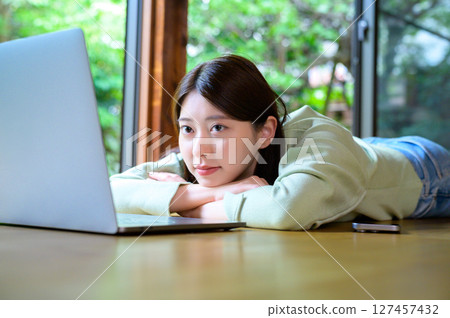 一個輕鬆的午後，一位女士躺在筆記型電腦前，雙臂當枕頭，安靜地休息 127457432