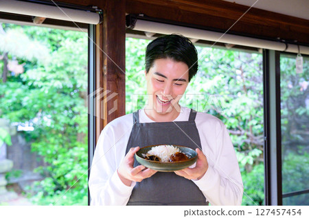 The smiling man is holding a plate of hamburger steak in both hands and looking down slightly, creating an impressive look. The smiling man is holding a plate of hamburger steak in both hands and looking down slightly, creating an impressive look. 127457454