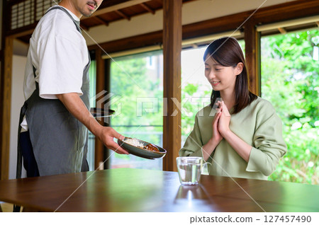 A warm moment in a Japanese restaurant with a man serving food and a woman responding with gratitude A warm moment in a Japanese restaurant with a man serving food and a woman responding with gratitude 127457490