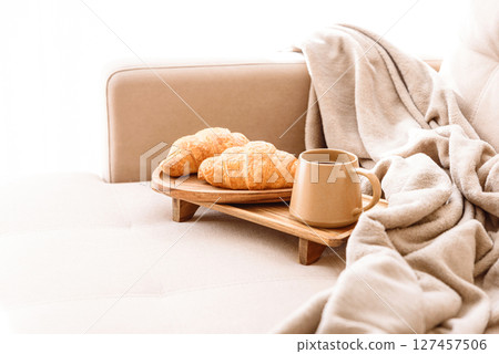 Coffee and croissants served on a wooden tray on a beige couch. Soft focus 127457506