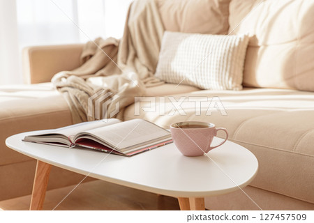 Cozy living room with a book and tea on a beige couch. Soft focus Cozy living room with a book and tea on a beige couch. Soft focus 127457509