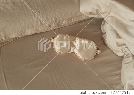 Silk sleep mask on a cozy beige bed. 127457512