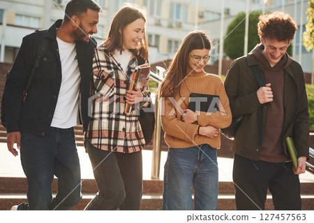 Front view. Four young students in casual clothes are together outdoors Front view. Four young students in casual clothes are together outdoors 127457563
