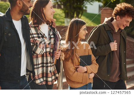 Four young students in casual clothes are together outdoors Four young students in casual clothes are together outdoors 127457565
