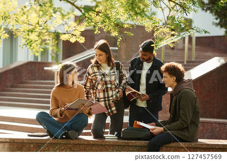 Tree with green leaves. Four young students in casual clothes are together outdoors 127457569