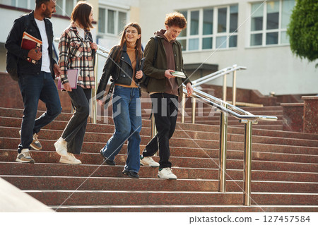 Going down the stairs. Four young students in casual clothes are together outdoors 127457584