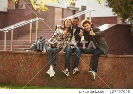 Three young students in casual clothes are together outdoors Three young students in casual clothes are together outdoors 127457668