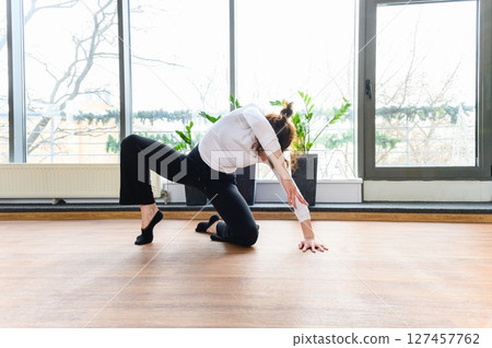Woman in modern dance floor pose near large window. 127457762