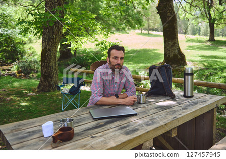 Man Enjoying a Relaxing Moment Outdoors with Coffee and Work Essentials Man Enjoying a Relaxing Moment Outdoors with Coffee and Work Essentials 127457945