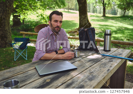 Man Enjoying an Outdoor Work Break Amidst Scenic Wilderness Man Enjoying an Outdoor Work Break Amidst Scenic Wilderness 127457946