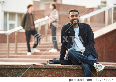 Positive Indian man. Young students in casual clothes are together outdoors 127457997