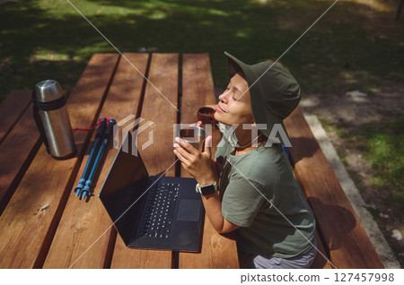 Digital Nomad Relaxes Outdoors at a Wooden Picnic Table While Working Remotely 127457998