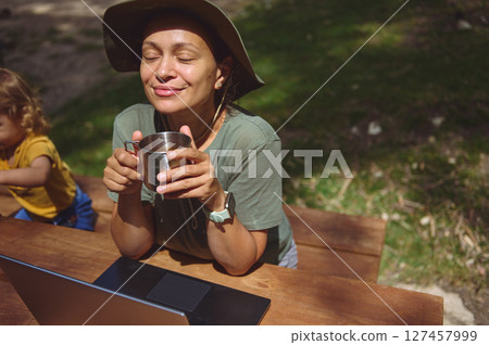 Woman Enjoying Online Work in Nature With a Refreshing Beverage 127457999