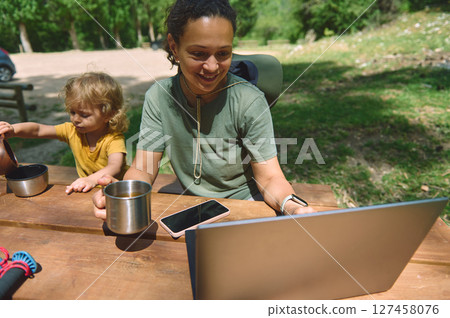 Woman Working Remotely in Nature While Caring for Child 127458076