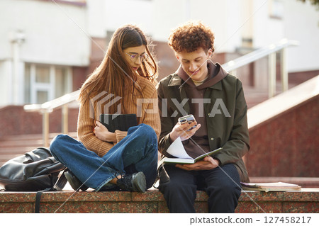 Man and woman students are together outdoors near university 127458217