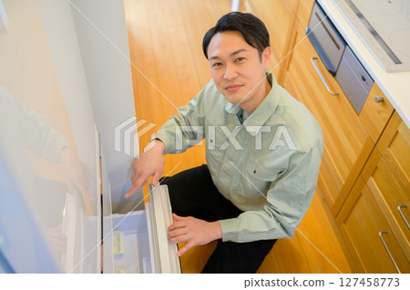 身穿工作服的日本男子檢查冰箱 身穿工作服的日本男子檢查冰箱 127458773